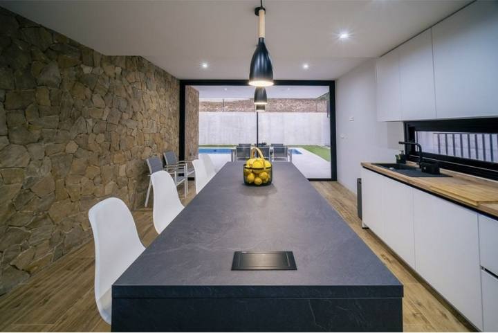 Cocina con isla oscura y pared de piedra